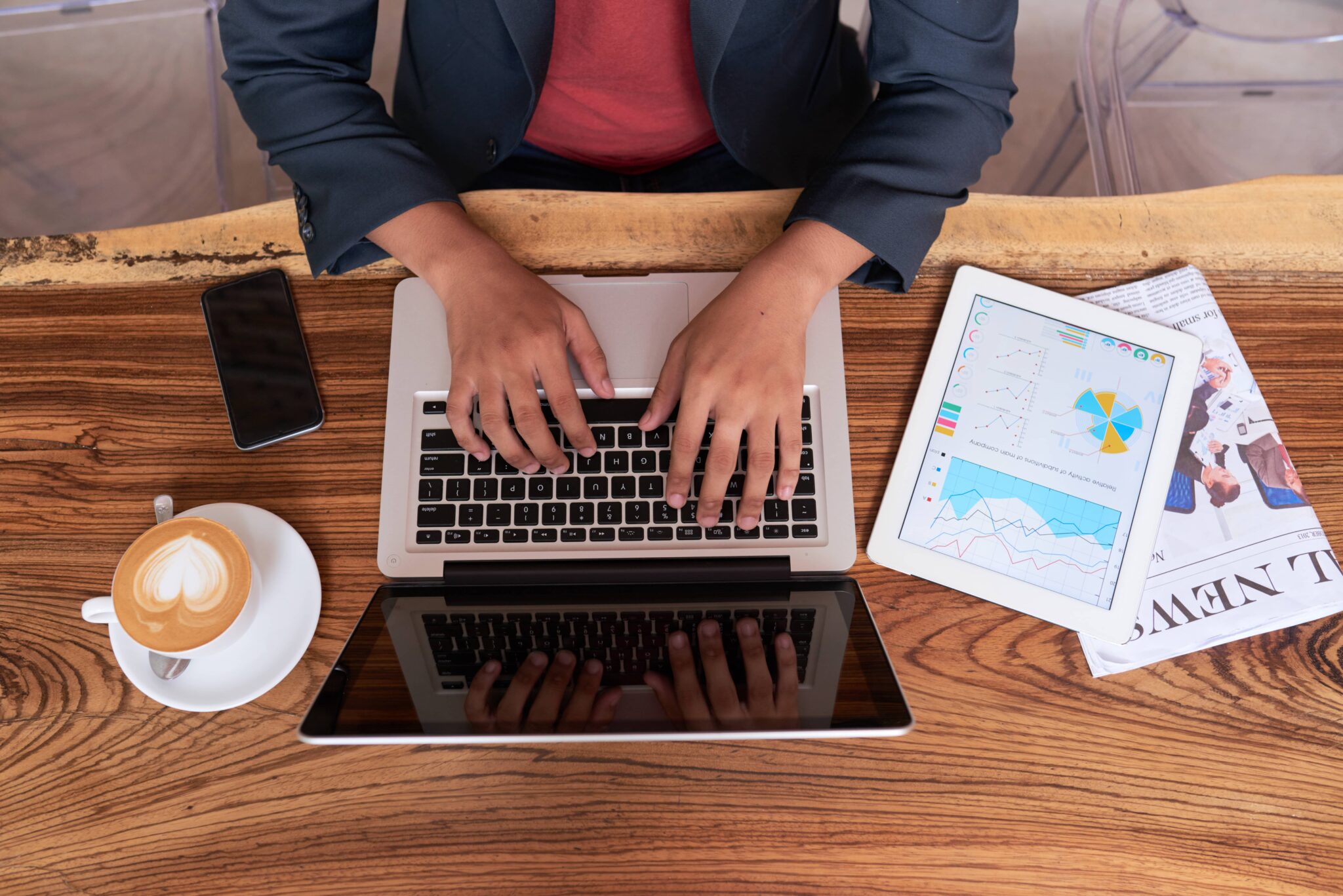 Person arbeitet am Laptop mit Statistiken auf Tablet, Kaffee daneben – Thema: Effiziente Datenanalyse im Homeoffice.