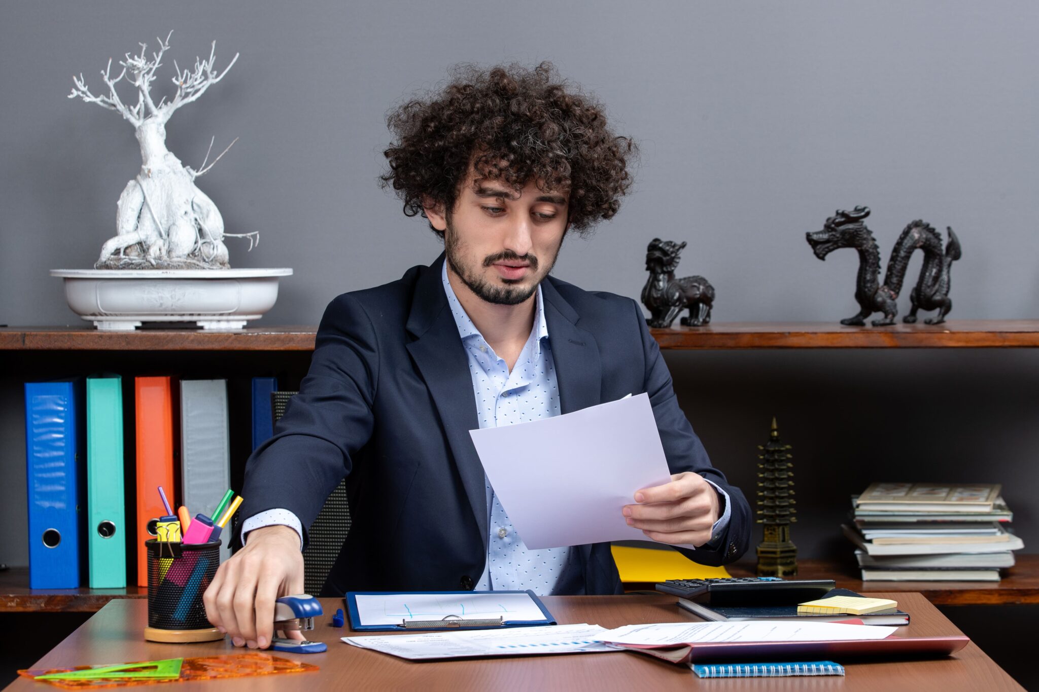 Junger Mann im Anzug prüft Dokumente im Büro, thematisch passend zum Beitrag über Effizienz in der Arbeitsorganisation.